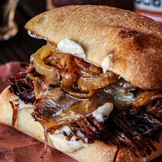 Ishgardian Onion Brisket: A delicious brisket, slow-cooked in Ishgardian onion soup, sliced, topped with white cheese, and placed atop a wonderfully fluffy bun. served with a side of au jus.