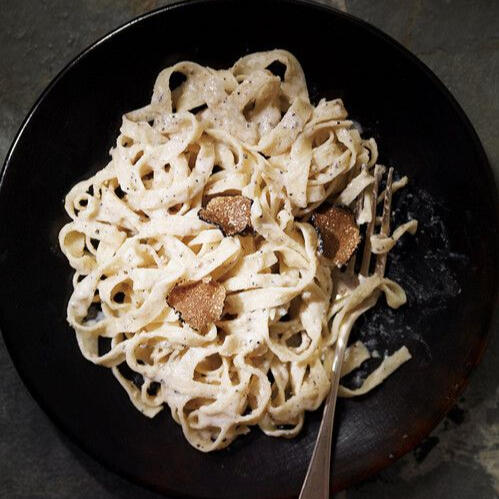 Tagliatelles aux truffes: Freshly made tagliatelles noodles made with a creamy cheese sauce and topped with thinly slice truffles.